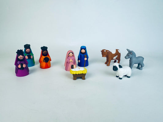Set of colorful nativity scene figurines on a light gray background