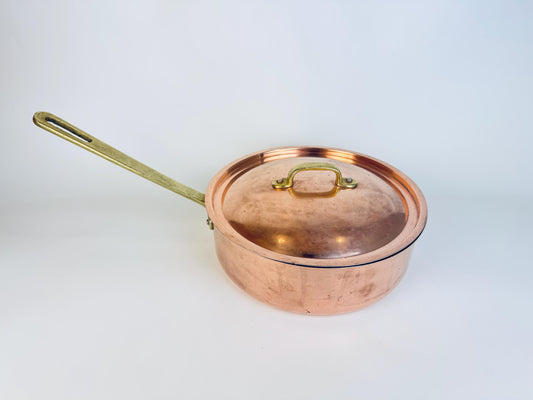 Copper saucepan with lid on a light gray background