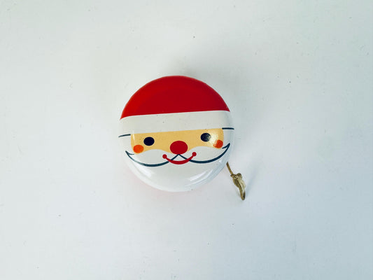 Vintage metal yo-yo featuring a cheerful Santa Claus face illustration with red hat, rosy cheeks, and white beard, shown against a plain white background.