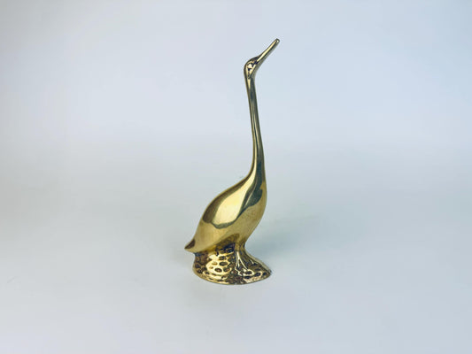 Vintage solid brass crane figurine with a long neck and textured base, displayed against a plain white background.