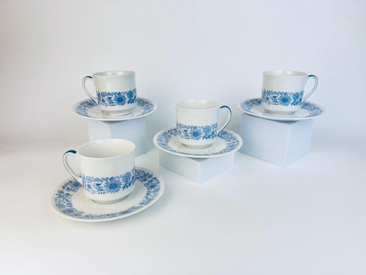 Set of four blue and white ceramic teacups and saucers on a white background