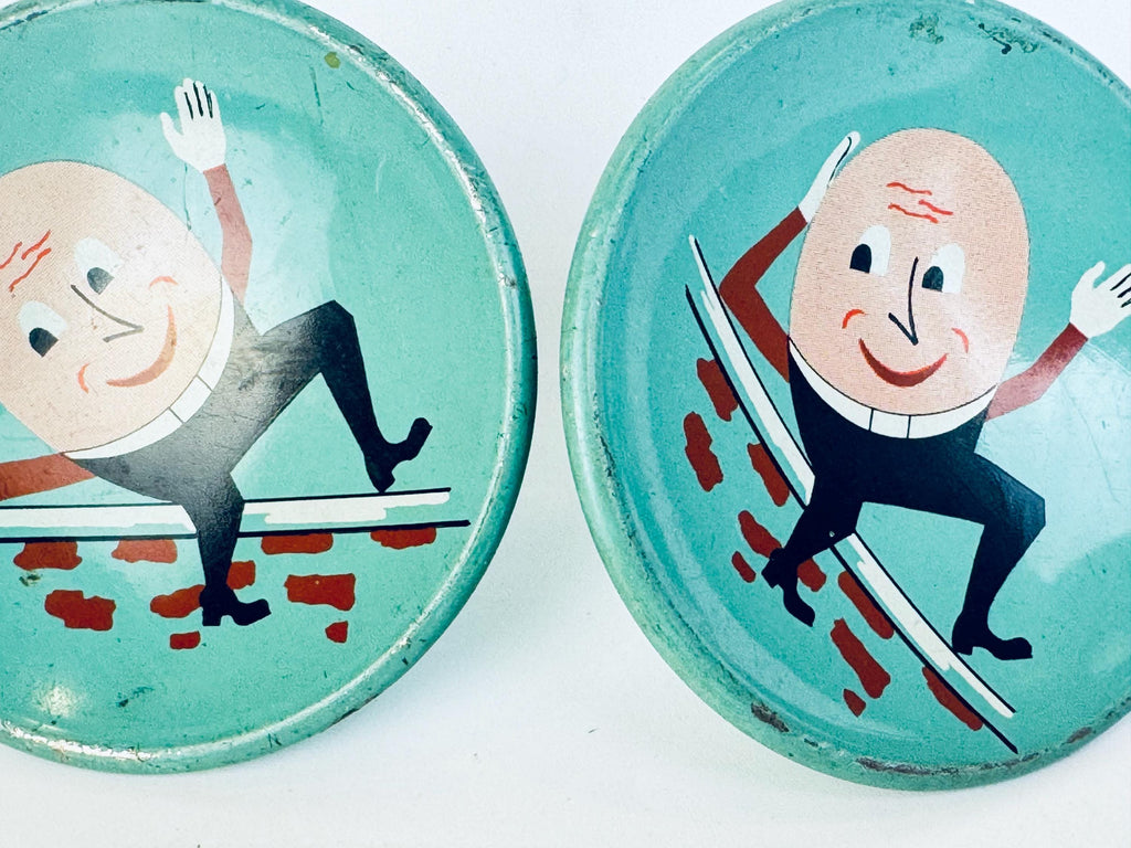 Two vintage metal storybook Humpty Dumpty character drawer knobs on a white background.