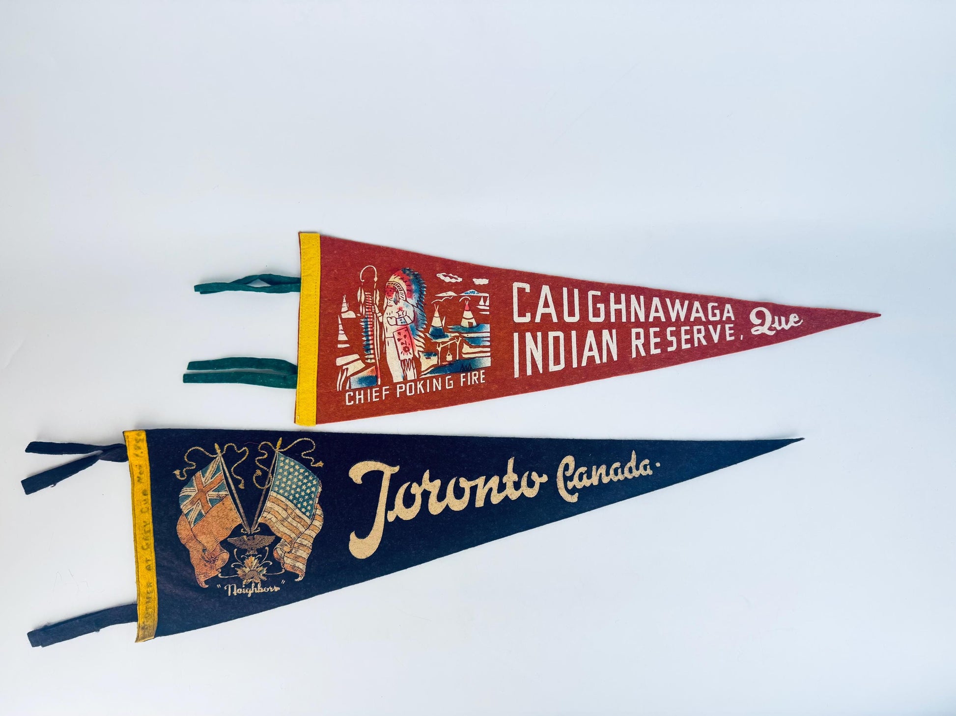 Two vintage-style pennants with 'Caughnawaga Indian Reserve, Que.' and 'Toronto Canada' text on a white background.