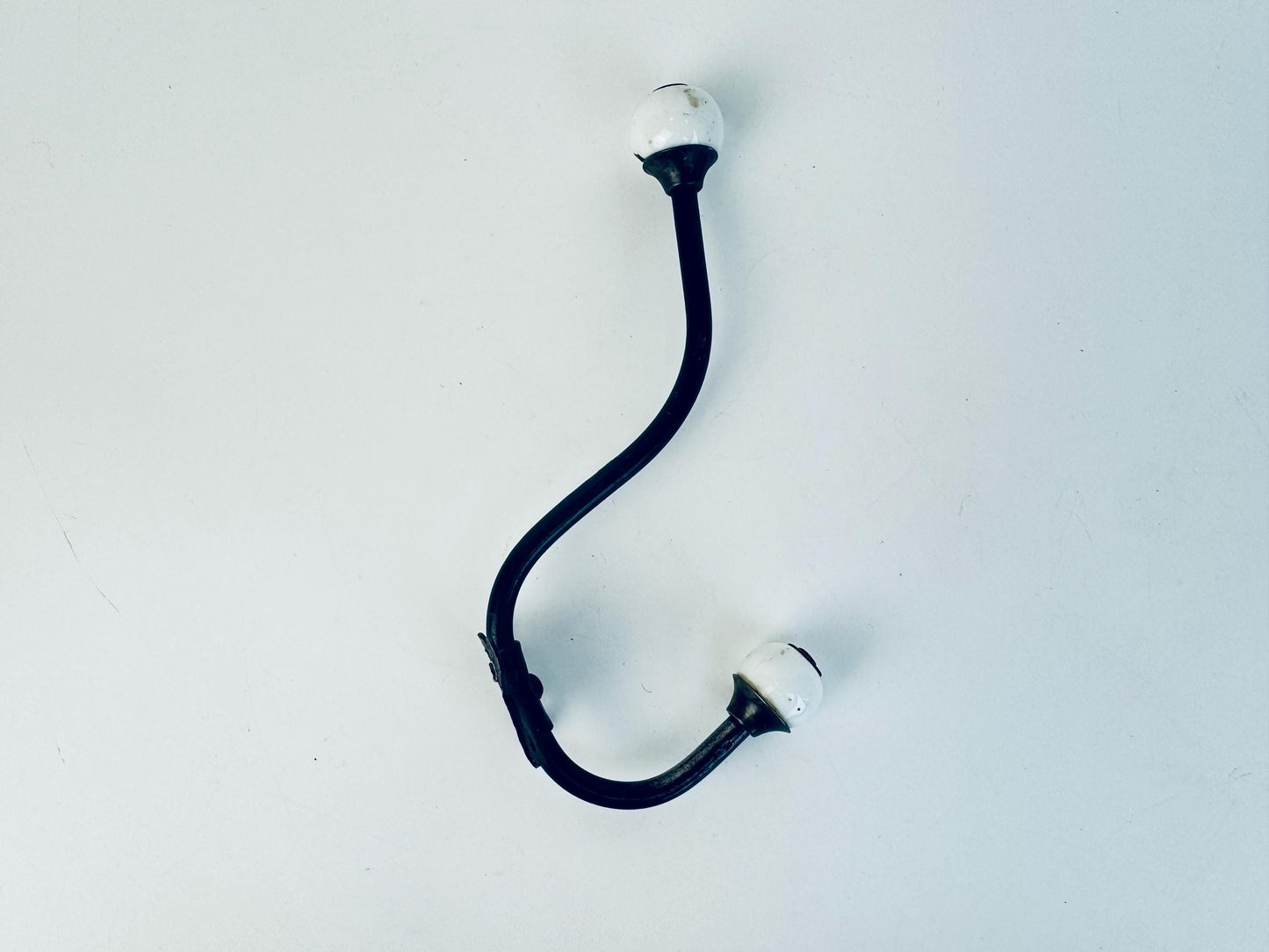Antique black iron with white porcelain ends double wall hook. 
