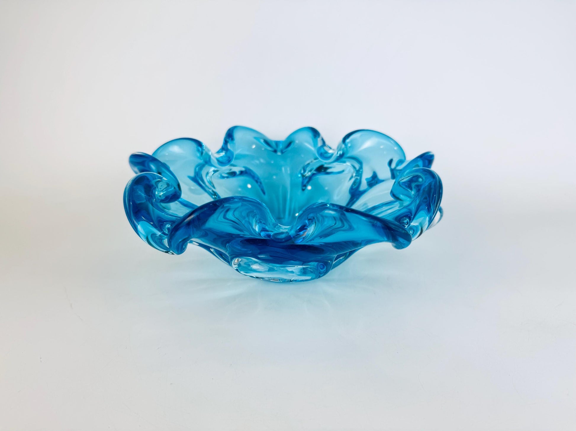 Blue glass bowl with wavy design on a white background