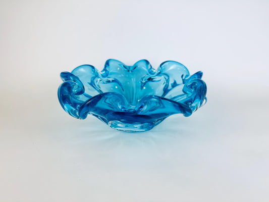 Blue glass bowl with wavy design on a white background