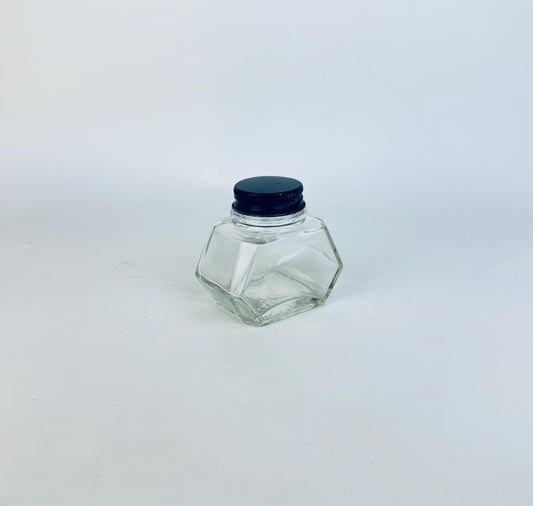 Clear hexagonal WATERMANS ink glass jar with a black lid on a light gray background