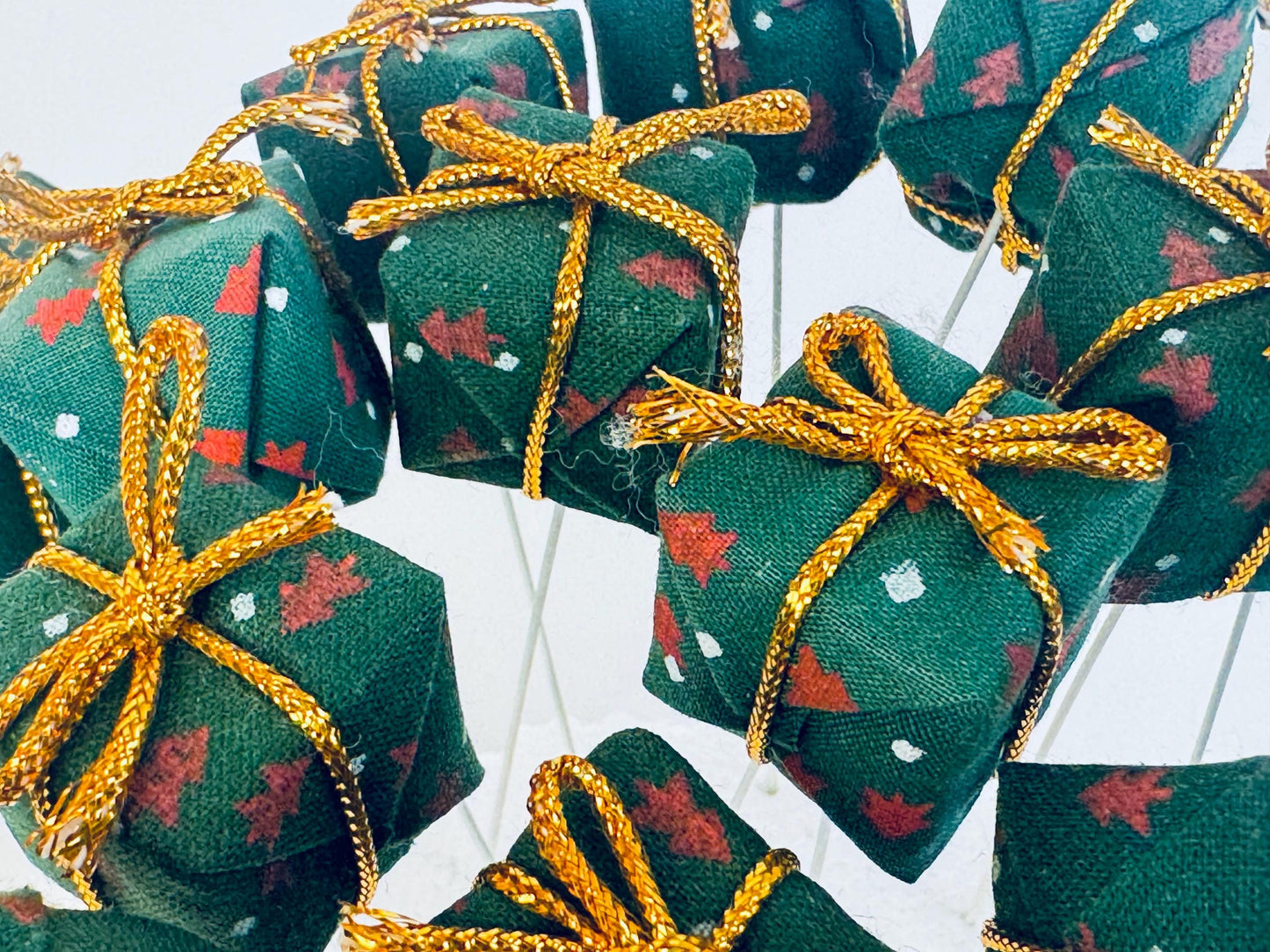 Green fabric gift boxes with gold ribbon craft picks on a white background