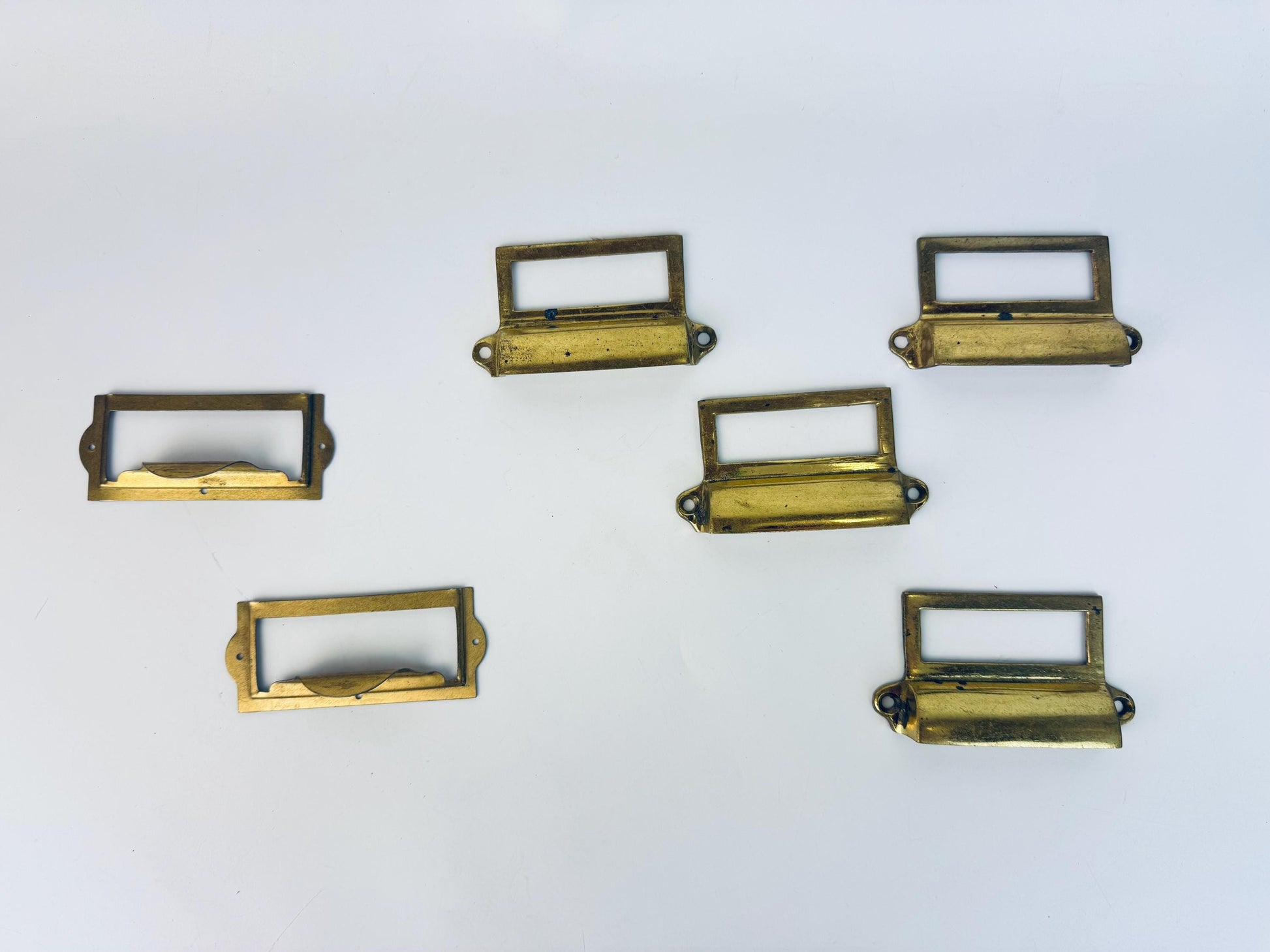 Set of six brass drawer pulls on a white background