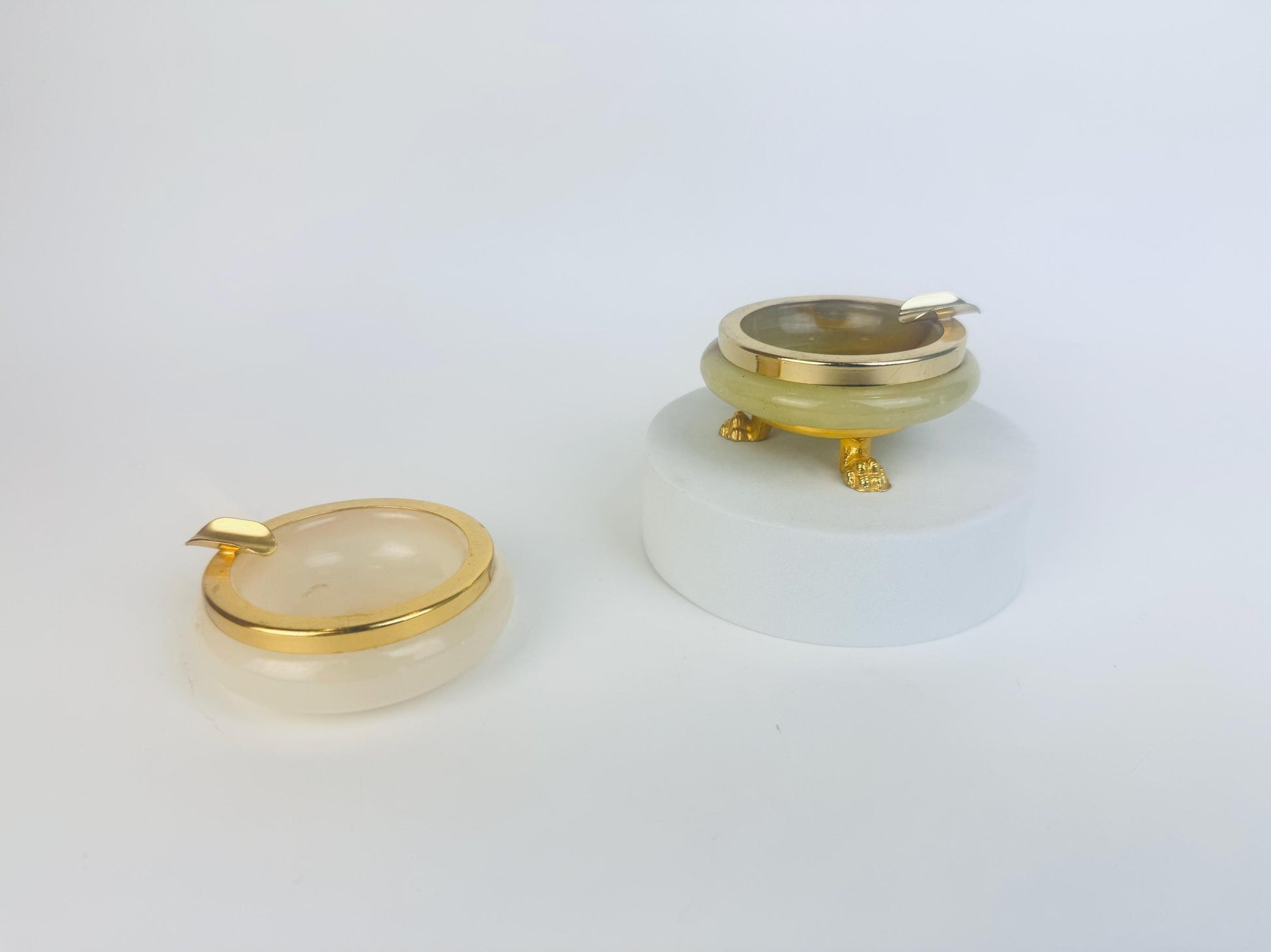 Two gold rimmed and onyx stone ashtrays  on a white background.