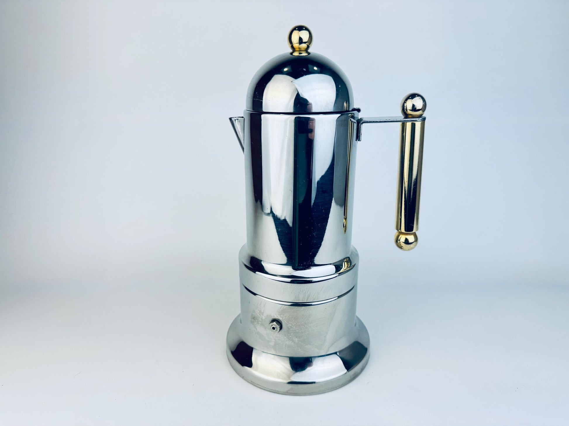 Vintage Italian stainless steel stovetop espresso maker featuring polished silver finish with gold accents on the handle and lid. The piece has a sleek cylindrical design with a domed top and a mid-century modern aesthetic, photographed against a white background.