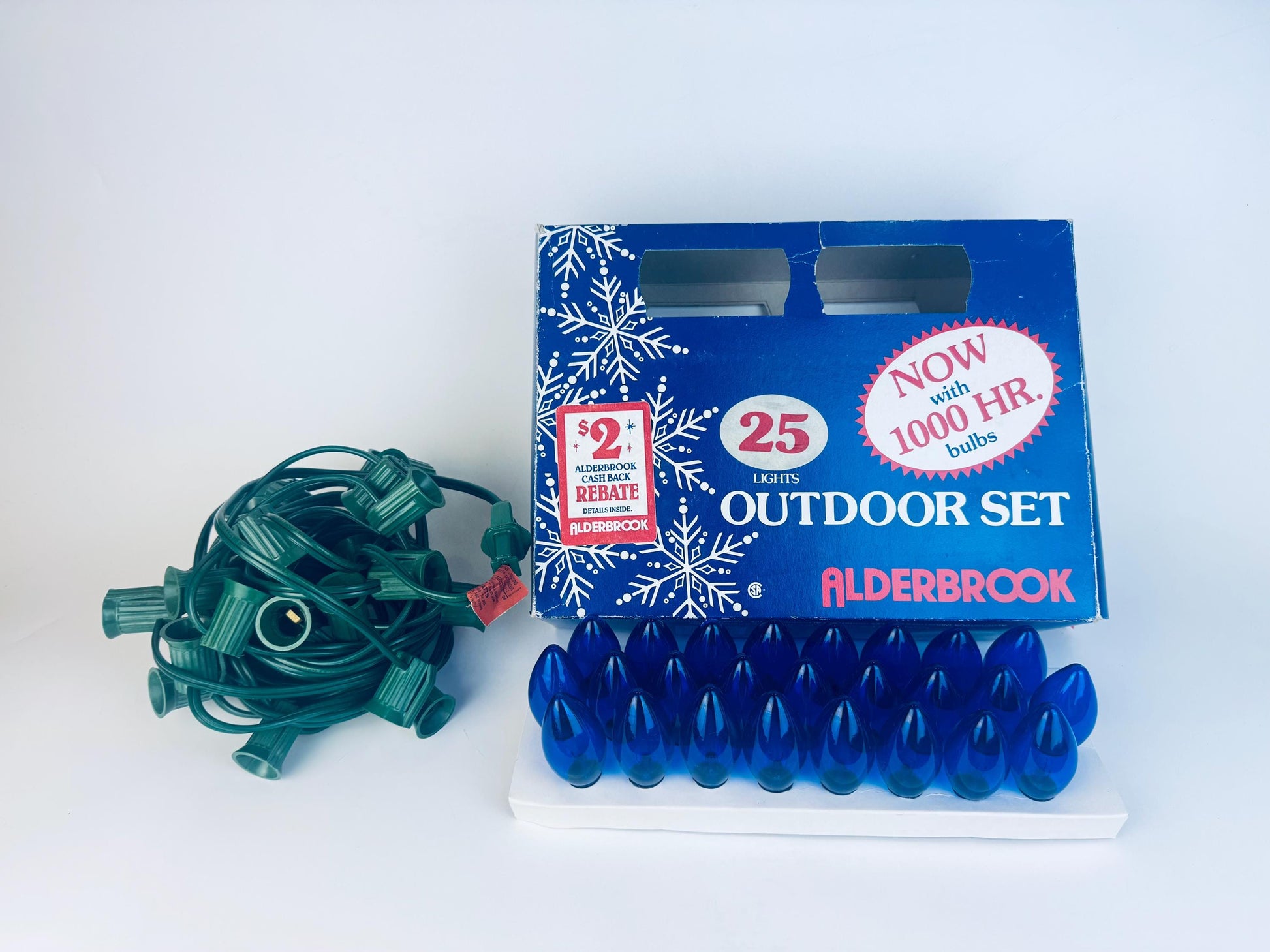 Vintage Alderbrook 25-light outdoor string light set with blue C7 bulbs, original box, and green wiring harness displayed together on a white background.