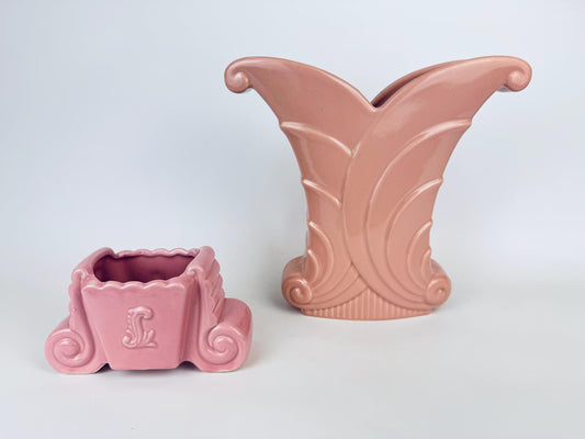 Two vintage pink Art Deco ceramic pieces displayed side by side: a large Abingdon fan-shaped vase with sculptural scroll details, and a smaller unmarked scroll-form planter with a scalloped rim.