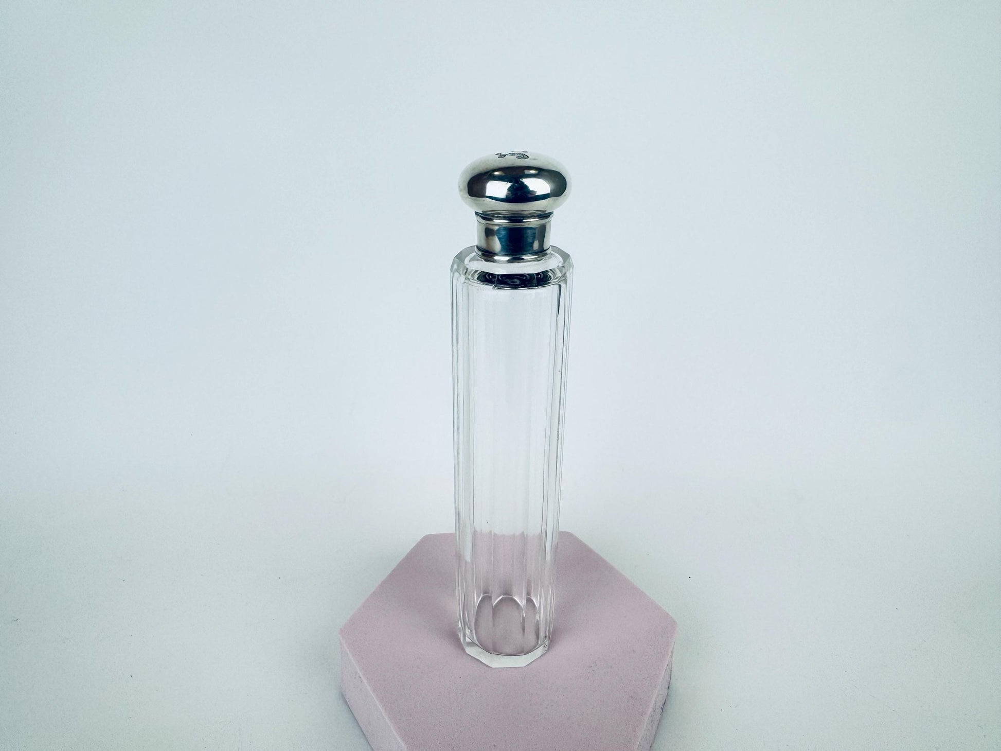 Tall 1938 fluted clear glass perfume bottle with sterling silver screw-top cap, shown upright on tabletop.