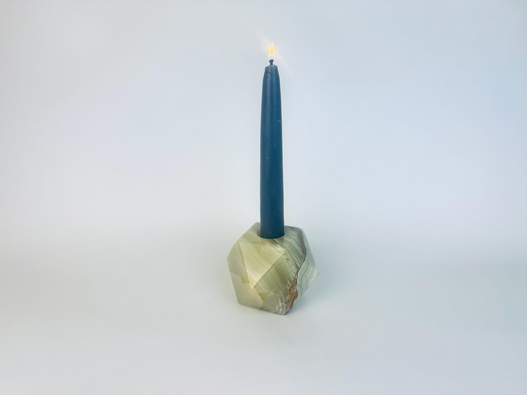 Candle in a geometric stone holder on a white background