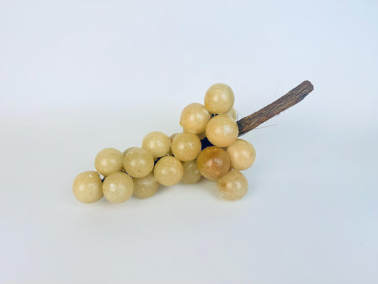 Vintage 1960s cream alabaster stone grape cluster with natural wood stem, shown resting on a white background.