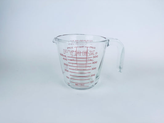 Vintage clear 2-cup Pyrex glass measuring cup with red metric and imperial markings, on white background.