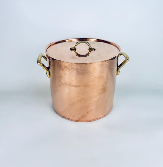 Vintage 1970s copper stock pot with brass handles and lid, shown upright on a white background, highlighting its warm patina and large cylindrical form.