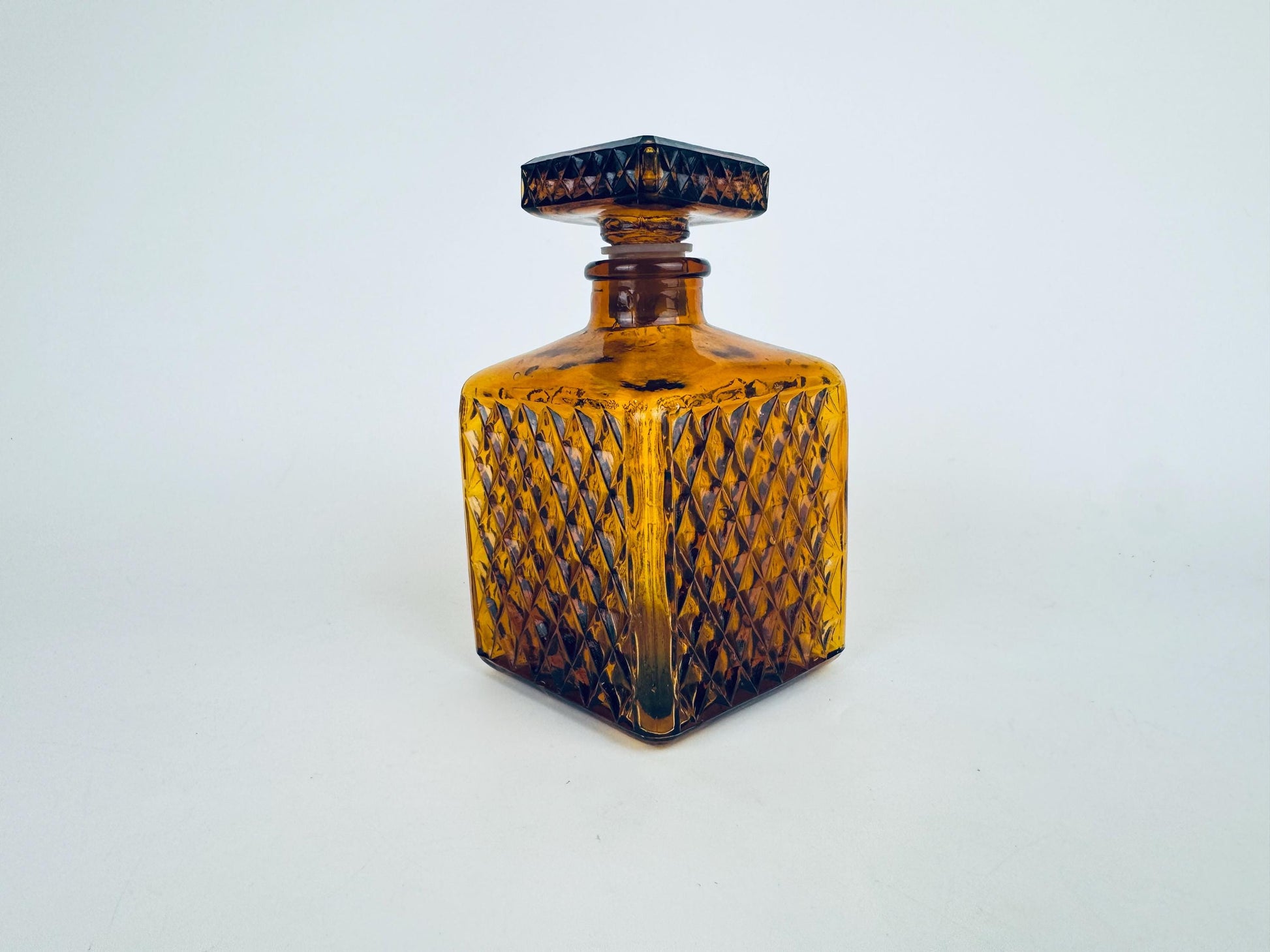 Vintage amber glass decanter with a diamond-pressed pattern and square stopper, shown standing upright against a plain background.