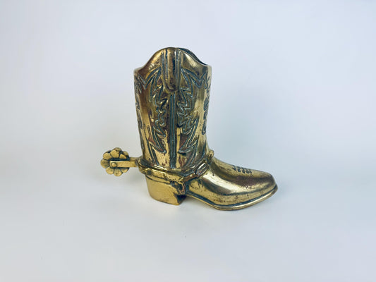 Vintage solid brass cowboy boot figurine with detailed raised stitching and a decorative spur, shown angled to highlight the patina and sculpted Western design.