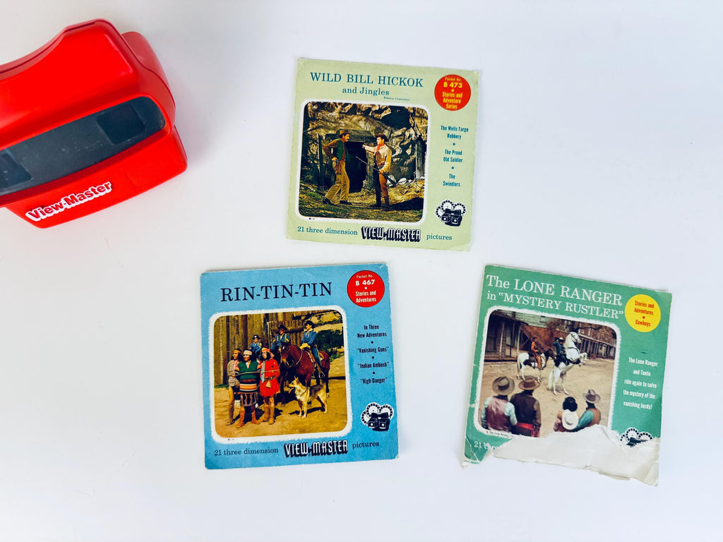 Three vintage 1950s Western View-Master packets displayed with a red View-Master viewer, including cowboy, frontier, and adventure scenes from classic mid-century television.