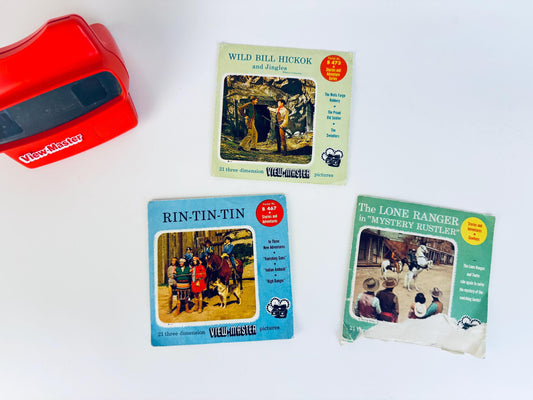 Three vintage 1950s Western View-Master packets displayed with a red View-Master viewer, including cowboy, frontier, and adventure scenes from classic mid-century television.
