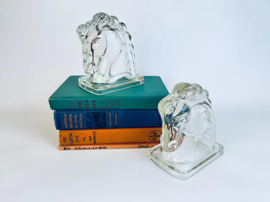 Pair of vintage clear glass horse head bookends with stylised manes displayed on a shelf.