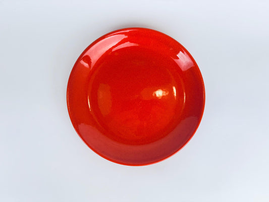 Bright vintage Waechtersbach red glazed ceramic dinner plate on white background, showcasing bold colour and smooth modernist silhouette.