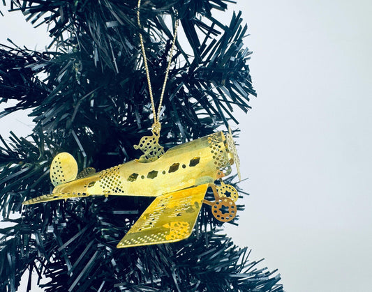 Vintage solid brass biplane airplane Christmas ornament with Merry Christmas engraving on wing, photographed on a white background.