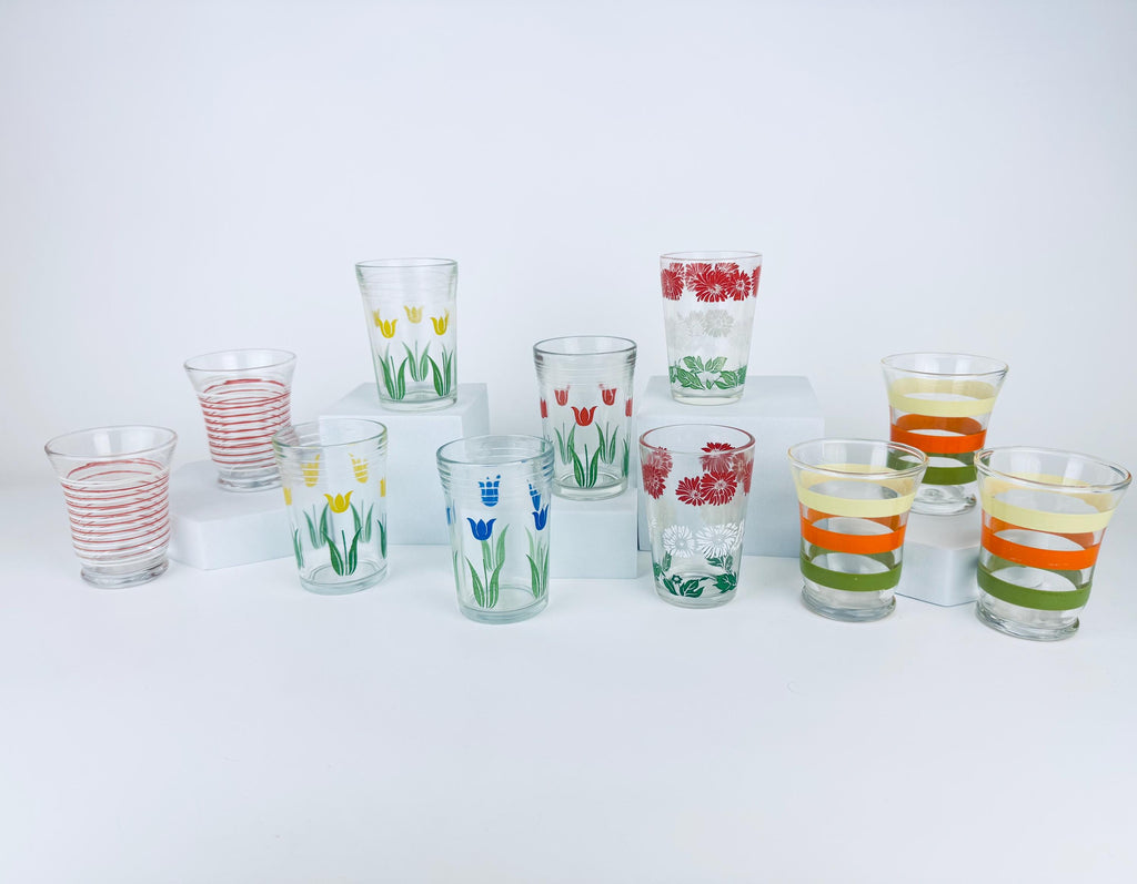 Vintage mid century patterned juice glasses with floral and striped designs displayed on white blocks.