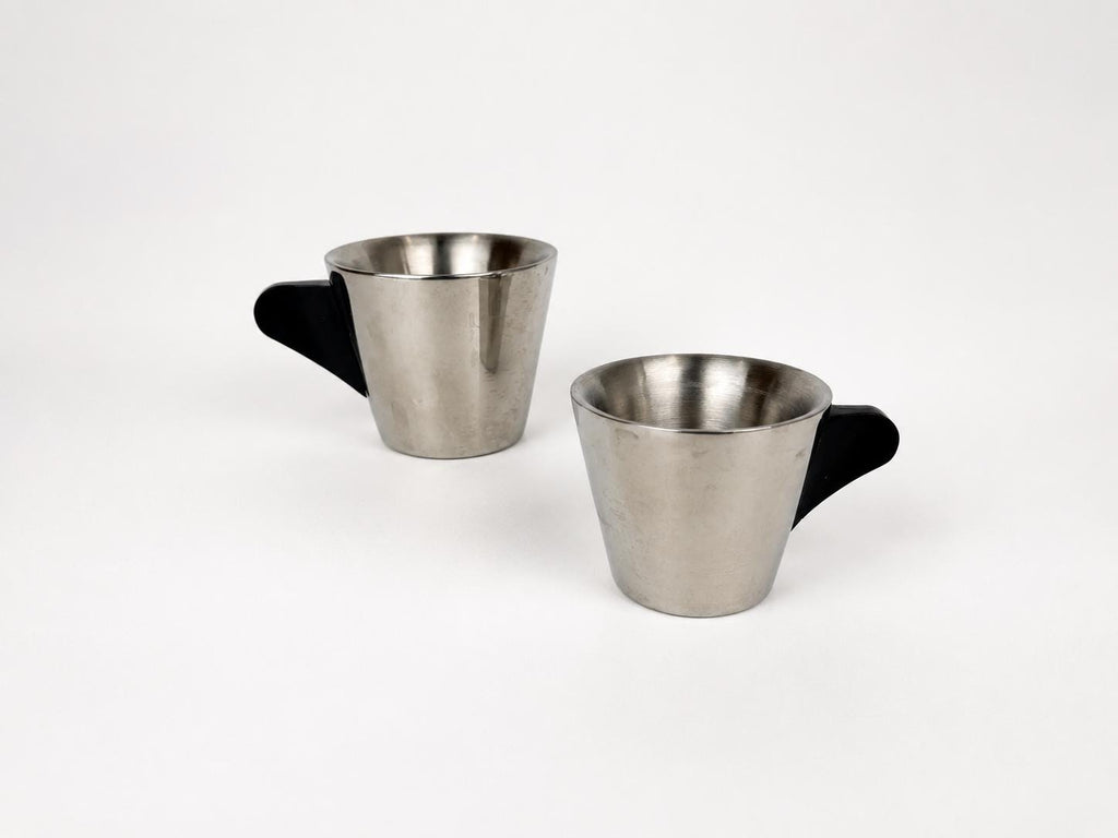 Two stainless steel coffee cups with black handles, shown on a clean white background.
